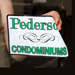 Black border and design with green Pederson Condominiums text on white rectangle custom static cling decal on window
