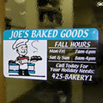 Custom window decal of multi-color baker man graphic on clear rectangle Joe's Baked Goods on window.