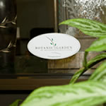 Green and brown leaf graphic on white vinyl oval Botanic Garden custom window decal in window