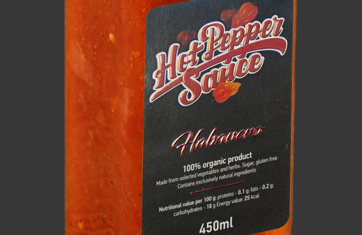 Custom foil labels on a habanero hot sauce bottle, adding a premium touch to the product packaging.