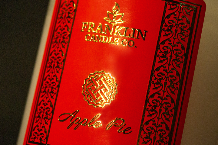 Gold foil embossed labels on a red candle package, adding a touch of elegance and luxury to the product presentation.
